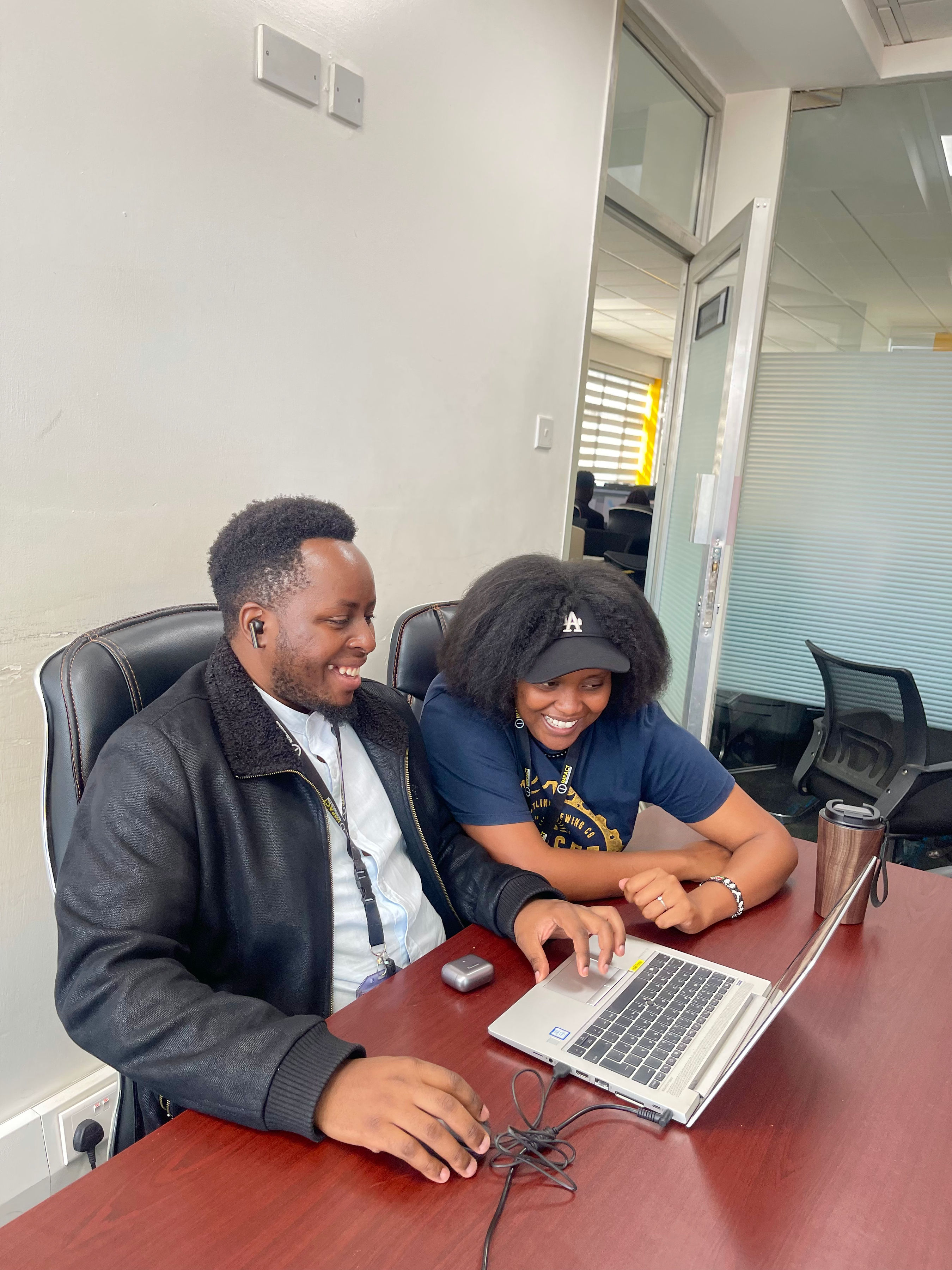 Two Impact Outsourcing reviewers working together at a laptop during live QA on the Nairobi delivery floor.