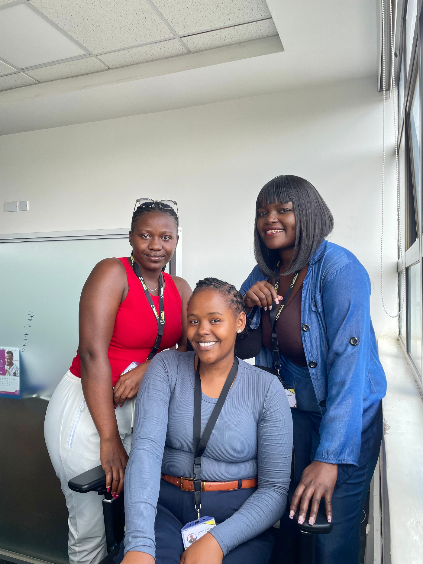 Three Impact Outsourcing team members gathered by the office window in Nairobi.